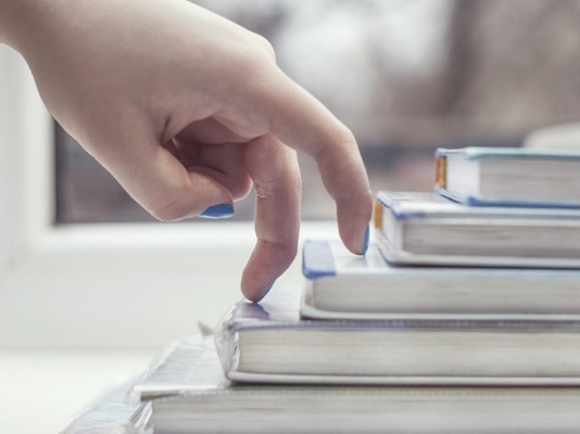 fingers walking up stack of books